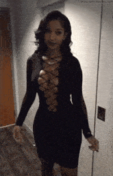 a woman in a black dress with a plunging neckline is standing in a hallway .