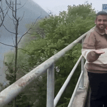 a man standing on a railing holding a piece of paper with a p on it