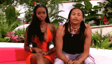 a man and a woman sit on a pink couch