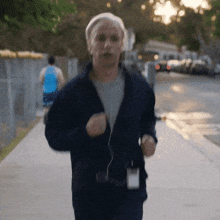 a man in a blue jacket is running down the sidewalk
