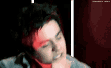 a close up of a person 's face with a red light behind him .