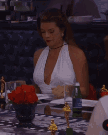 a woman in a white dress sits at a table with a bottle of aquafina water in front of her