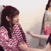 a woman in a pink and white striped shirt is holding another woman 's hand