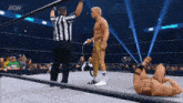 a wrestler is laying on the ground in a wrestling ring with a referee standing behind him