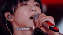 a close up of a person singing into a microphone with chinese writing on the bottom right