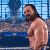 a shirtless wrestler stands in a ring with the word general on his belt
