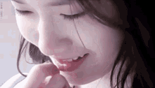 a close up of a woman 's face with her eyes closed and her hand on her face .