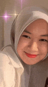 a woman wearing a hijab is smiling with a pink star in the background