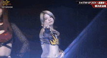 a woman in a wrestling outfit is standing on a stage and making a funny face .