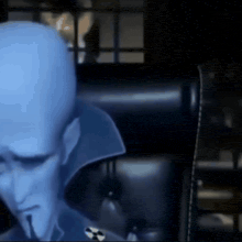 a man with a very large head is sitting in a dark room