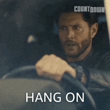 a man is driving a car with the words hang on written above him