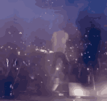a blurry picture of a person standing on a stage in front of a crowd at a concert .