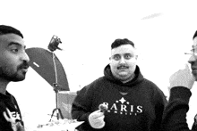 a man wearing a baris sweatshirt holds something in his hand in a black and white photo