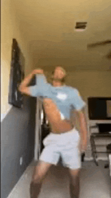 a shirtless man is dancing in a living room with his shirt off .
