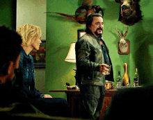 a man in a leather jacket is holding a glass in front of a woman