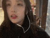 a close up of a woman wearing headphones and a black jacket .