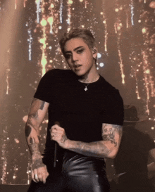 a man with tattoos on his arms is singing into a microphone on stage