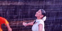 a woman in a white dress is dancing in the rain .