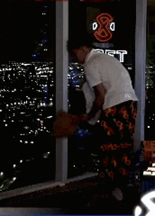 a man in a white shirt is standing in front of a window with a neon sign that says yt