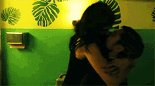 a man and a woman are kissing in a bathroom with a green wall .