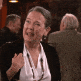 a woman wearing a black cardigan and a white shirt is making a face