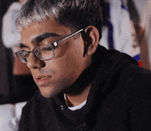a young man wearing glasses and a black hoodie