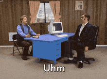 two men are sitting at a desk with a computer and the word uhm is on the bottom right
