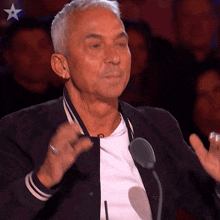 an older man speaking into a microphone with a star on his chest