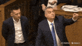 a man in a suit and tie is standing next to another man