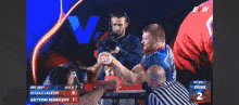 a man in a blue shirt with the letter b on it is arm wrestling another man