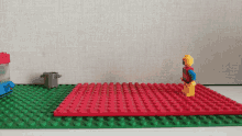 a lego figure is standing on a red and green brick mat