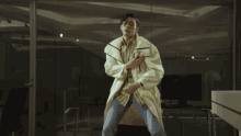 a man in a white coat and glasses is standing in front of a computer monitor