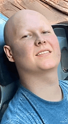 a bald man in a blue shirt is smiling while looking up .