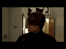 a man in a daredevil mask is standing in a hallway