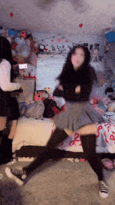 a girl is dancing in a room with stuffed animals on the wall and a hello kitty sign on the window