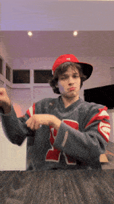 a young man wearing a red hat and a sweater with the letter r on it