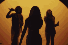 three women singing in front of a yellow background with nly written in the corner
