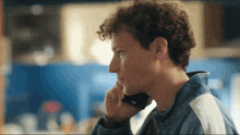 a young man with curly hair is talking on a cellphone