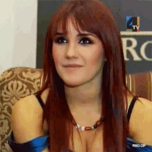 a woman with red hair is sitting in front of a sign that says 4tv