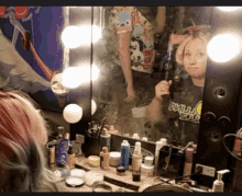 a woman taking a selfie in front of a mirror wearing a black shirt that says ' nirvana ' on it