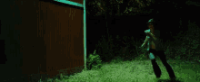 a woman in a crop top and black pants is running in the grass at night