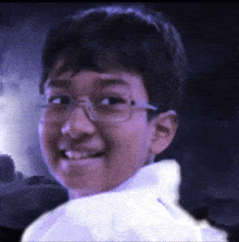 a young boy with glasses and a white shirt is smiling