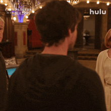 a man in a black shirt is standing in front of a sign that says hulu