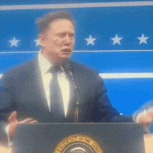 a man in a suit and tie is standing at a podium with the president of the united states logo on it