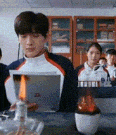 a group of people are sitting at a table in a classroom . one of the students is looking at a tablet .