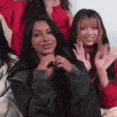 a group of young women are sitting next to each other and waving their hands .