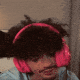 a man wearing pink headphones is sitting on a bed .