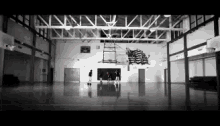 a black and white photo of a basketball court with a mural on the wall