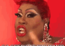 a drag queen with red hair and earrings says " do what you want " on a red background