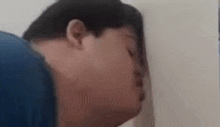 a man is leaning his head against a wall with his eyes closed .